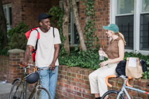 man met fiets praat met vrouw die naast een huis zit